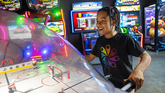 Kid playing air hockey.