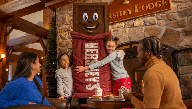 Brother and sister hugging Hershey character inside Lodge lobby.