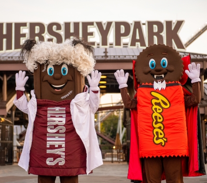 Hershey and Resses dressed up for Halloween and posing outside of Hersheypark entrance sign.