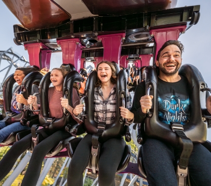 Two girls with giant smiles on their faces, hold hands as they float on the Intercoastal Waterway leaving Skyrush in the distance behind them.