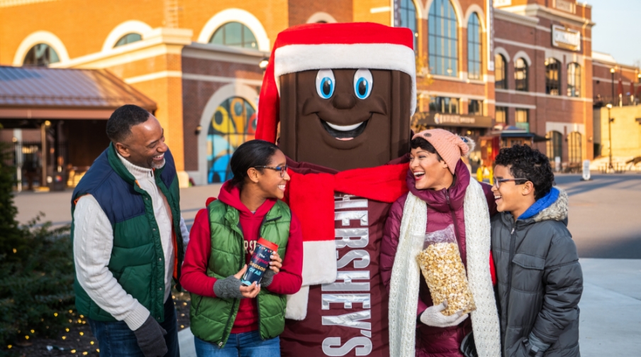 Family of four posing with Hershey character dressed for winter.